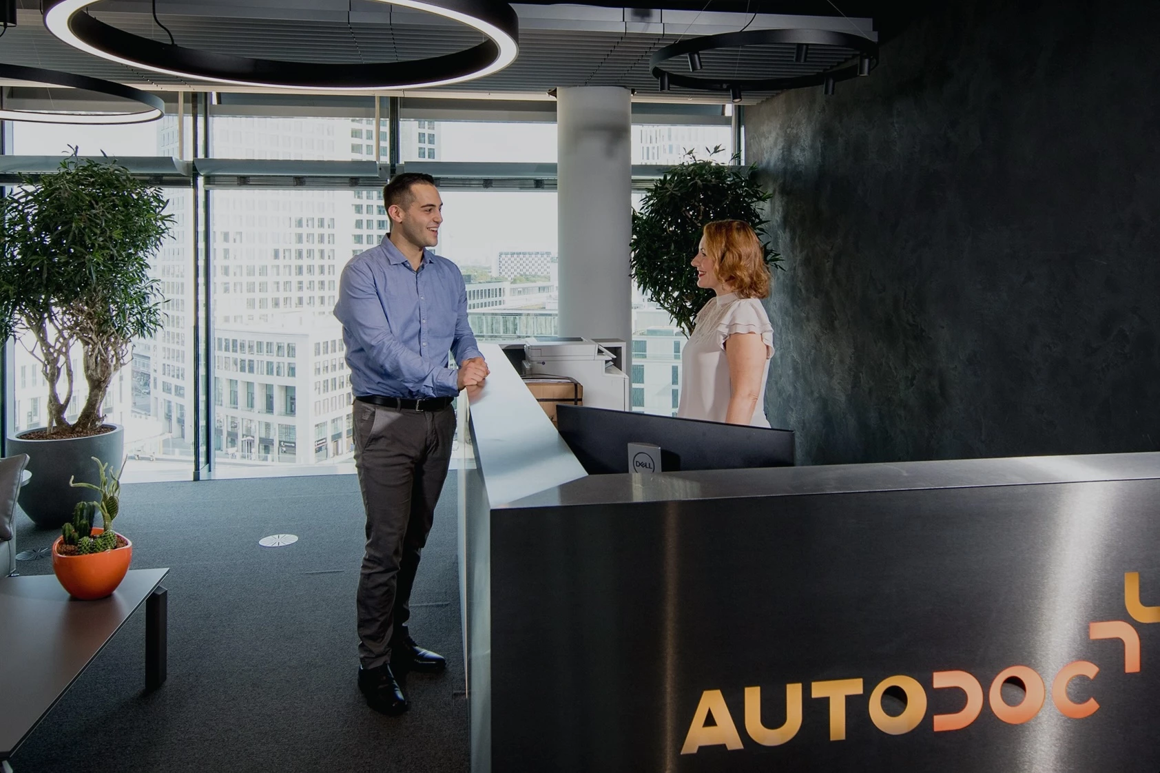 Modern Autodoc office reception area with a man talking to a receptionist at the front desk