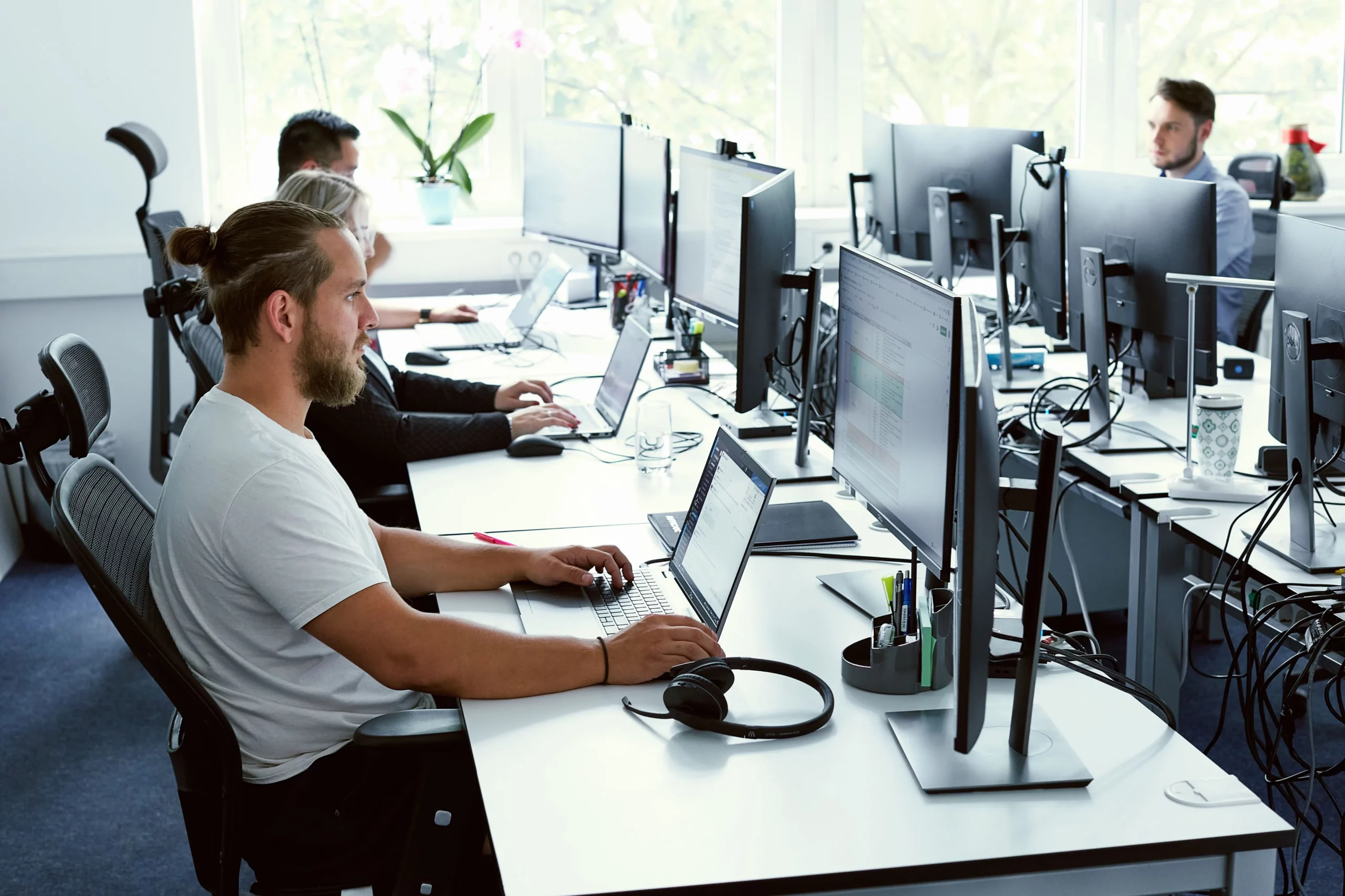 Team of employees working at computers in a modern open-space office.