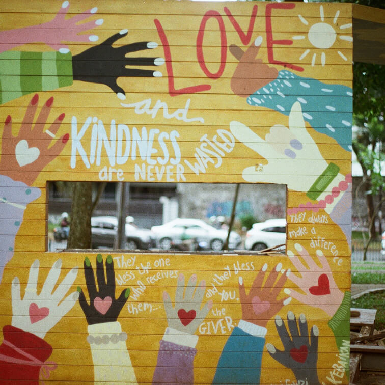 A yellow wall with painted hands and words by kids
